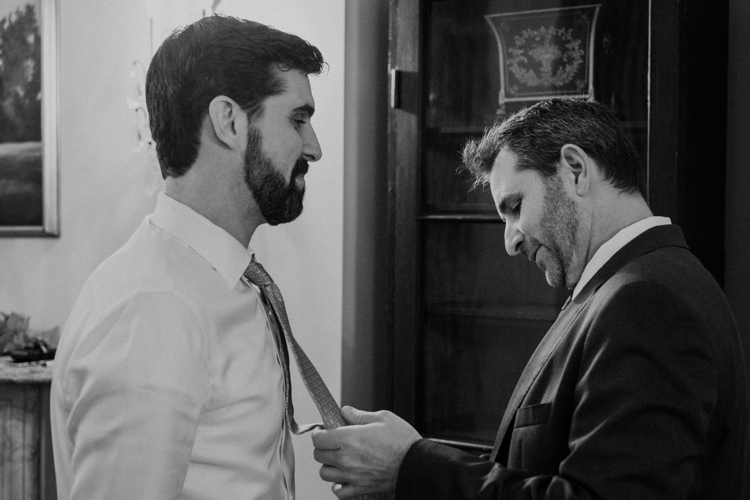 groom's brother helps tie his tie for wedding