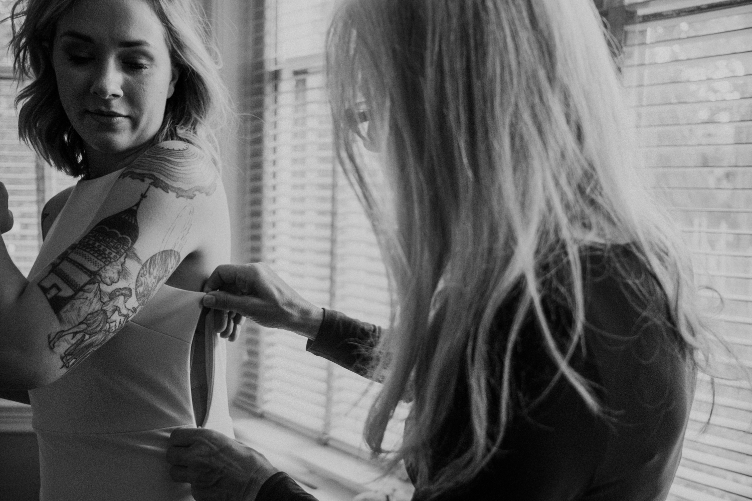 mother helping bride into her wedding dress