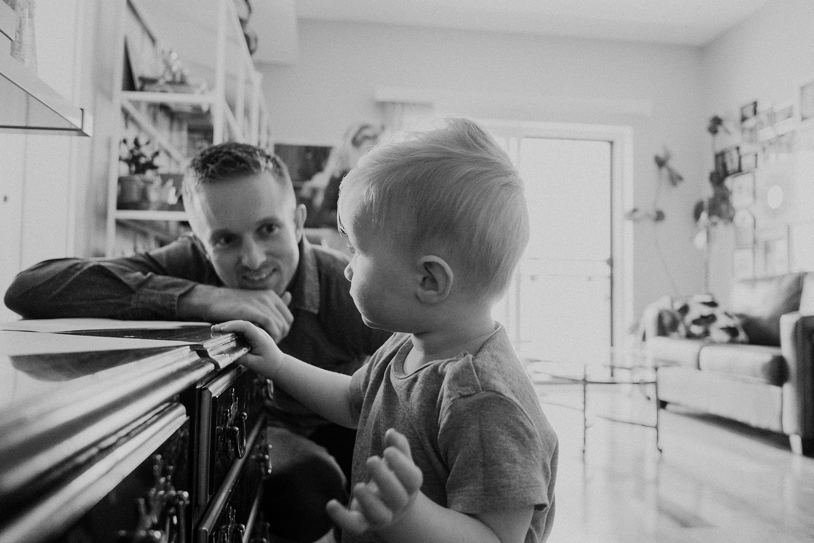 A father looks on while his son makes a drawing on paper in their apartment in Washington, DC.