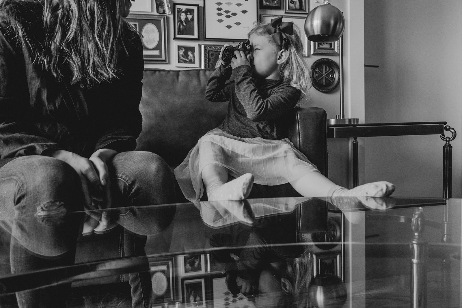 A little girl takes a picture of her mother while seated on a couch in their apartment in Washington, DC.