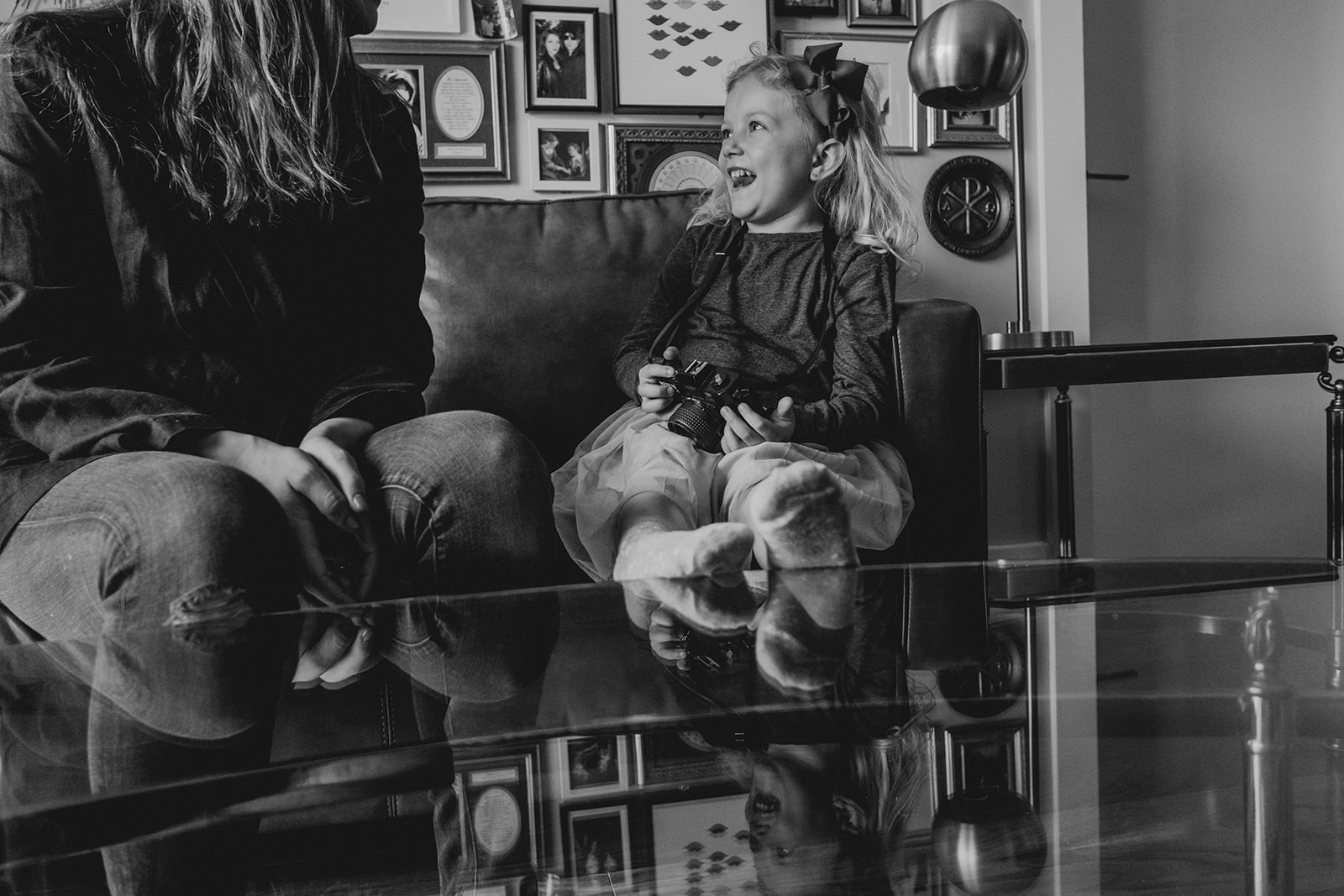 A little girl laughs while seated on a couch next to her mother in their apartment in Washington, DC.