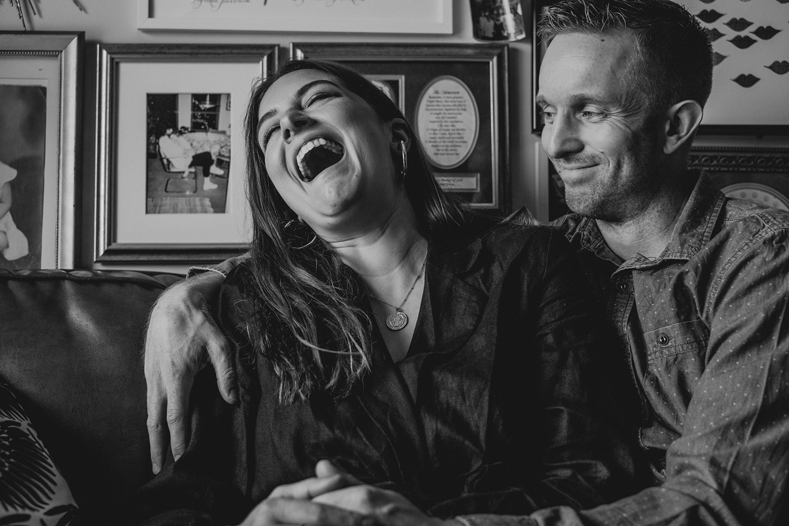 A woman laughs while sitting next her her husband on a couch in their apartment in Washington, DC.