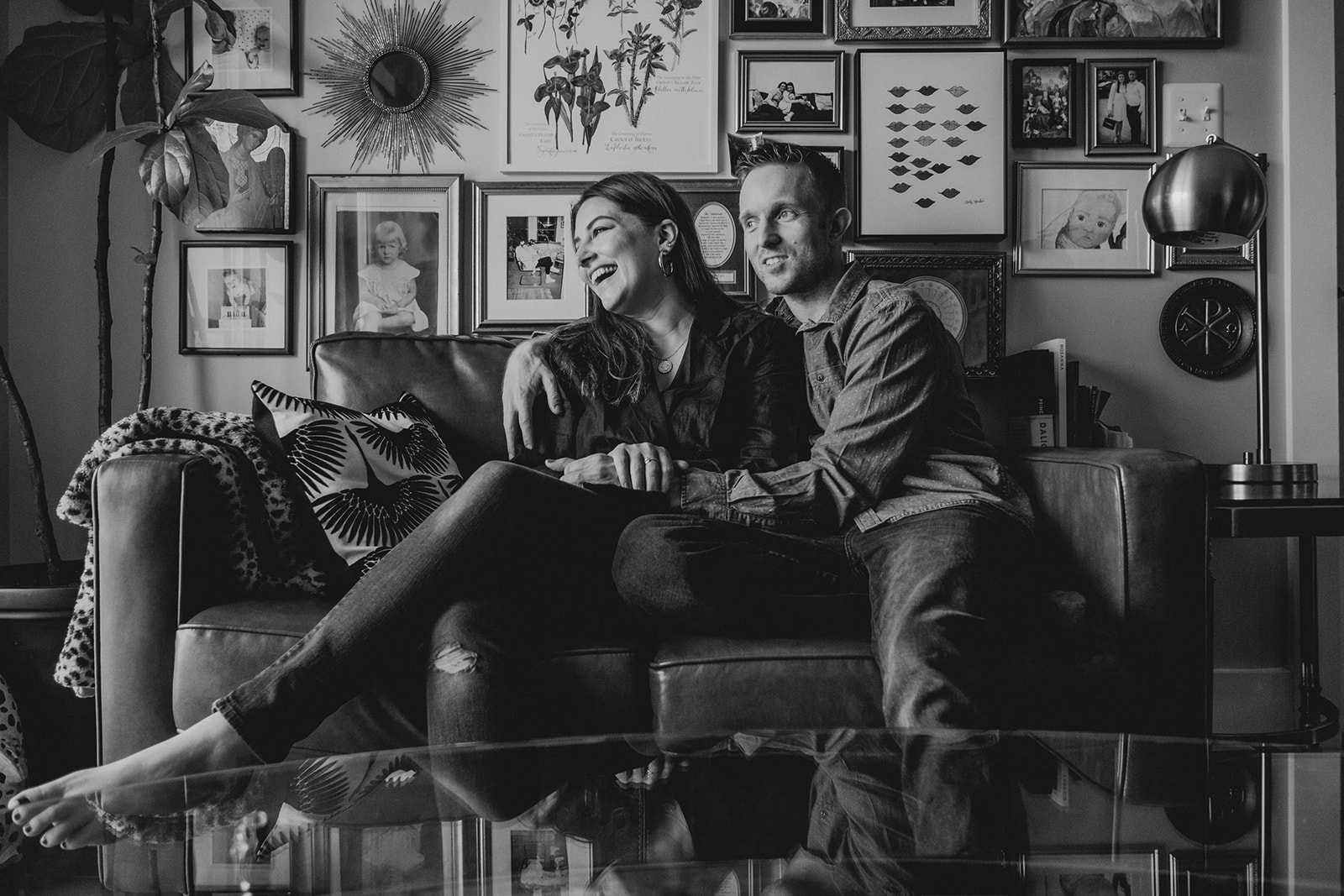 A husband and wife laugh together while sitting on a couch in their apartment in Washington, DC.