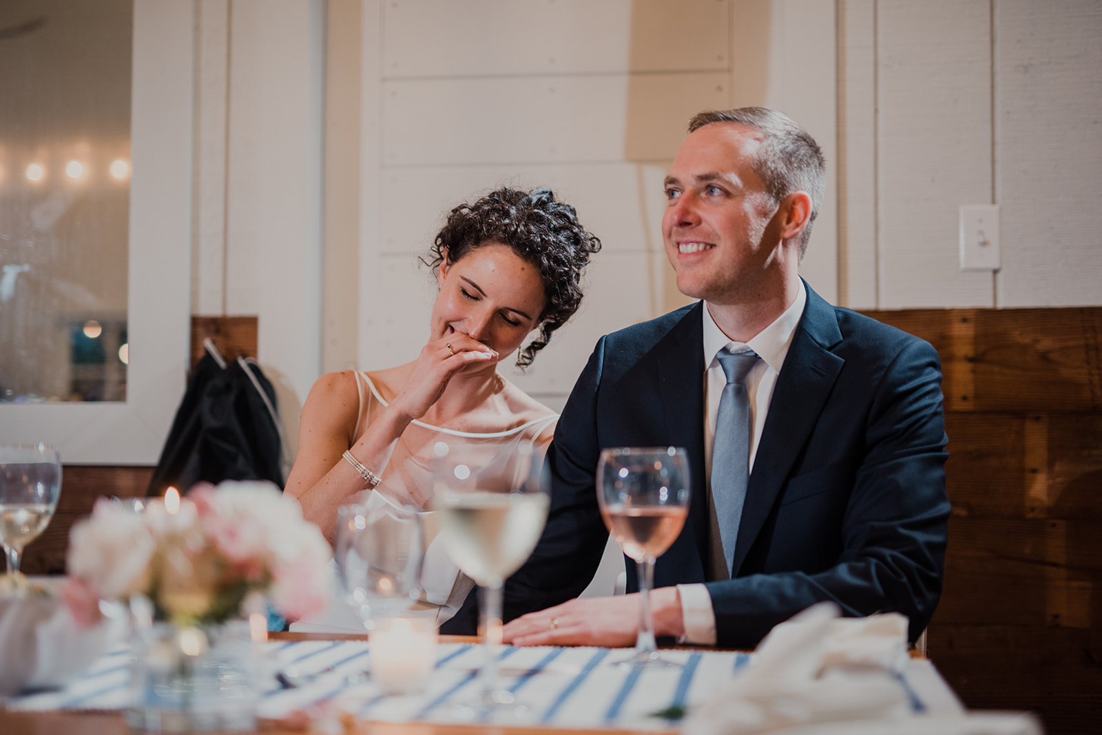 A bride and groom laugh during toasts at their wedding reception at Blue Hill Farm in Waterford, VA.