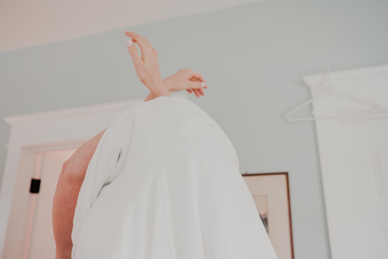 A bride's hands emerge from her wedding dress while she gets ready for her outdoor wedding ceremony at Blue Hill Farm in Waterford, VA.