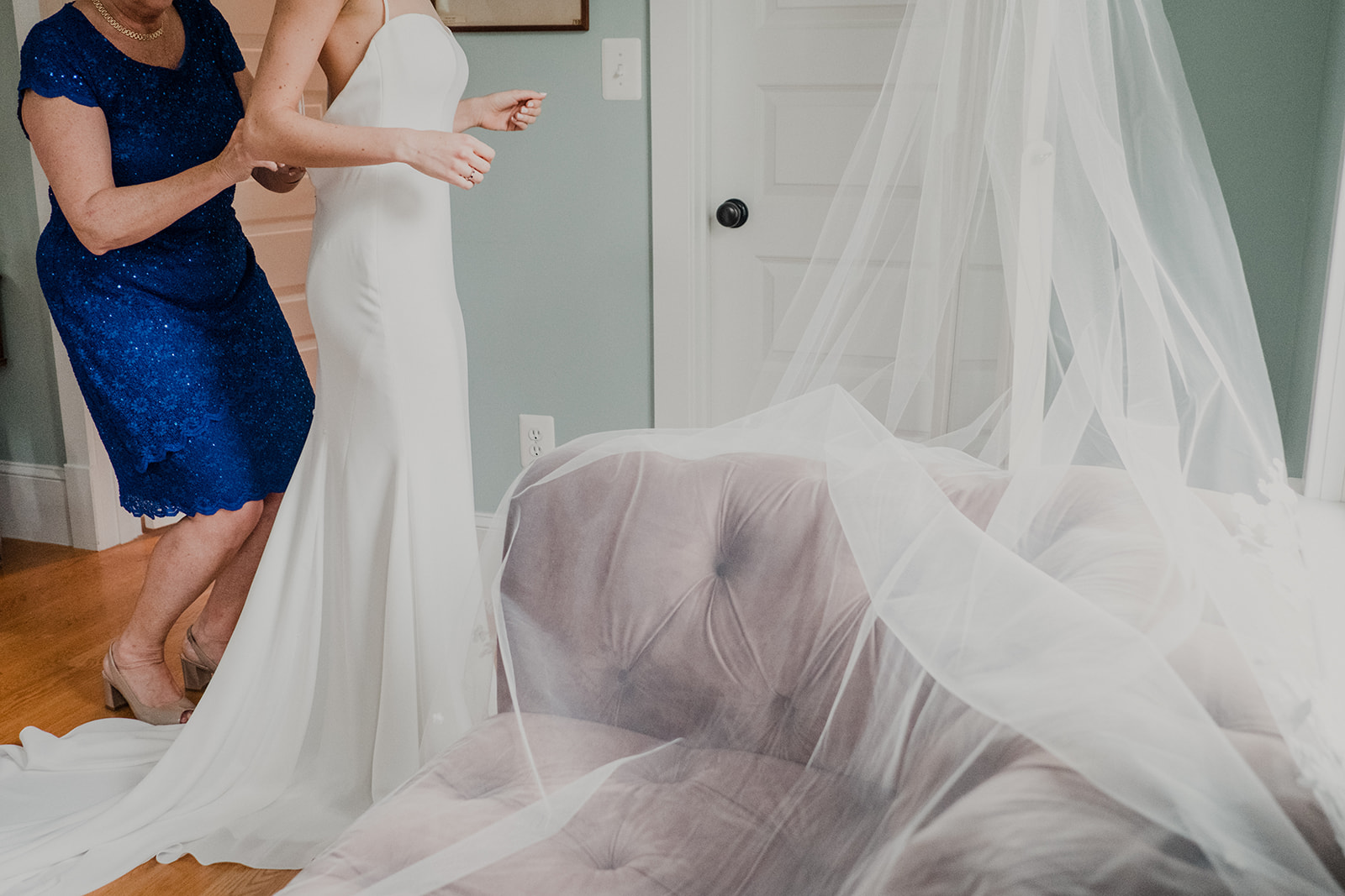 The mother of the bride helps her daughter get her dress zipped up before her outdoor wedding ceremony at Blue Hill Farm in Waterford, VA.