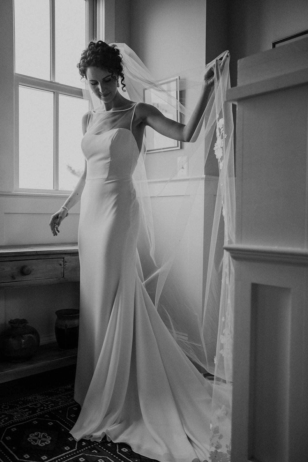 A bride fixes her veil on her way down the stairs in the house at Blue Hill Farm in Waterford, VA as she goes out to her outdoor wedding ceremony. 