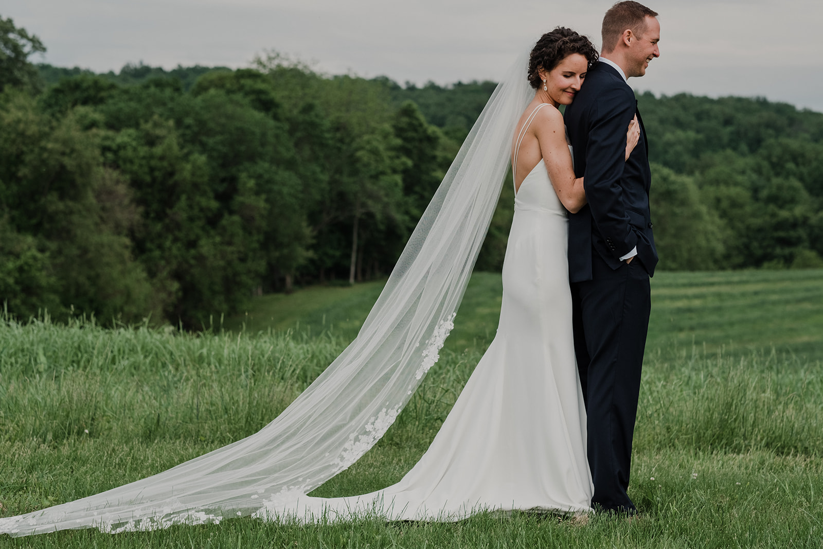 A bride holds her groom before he turns around for a first look before their outdoor wedding ceremony at Blue Hill Farm in Waterford, VA.