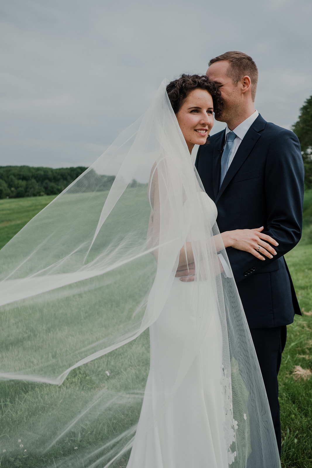 A long veil trails behind a bride during her first look with her groom before their outdoor wedding ceremony at Blue Hill Farm in Waterford, VA.