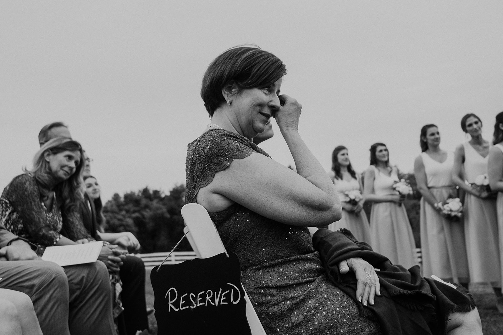 The mother of the bride wipes aways tears during her daughter's outdoor wedding ceremony at Blue Hill Farm in Waterford, VA.