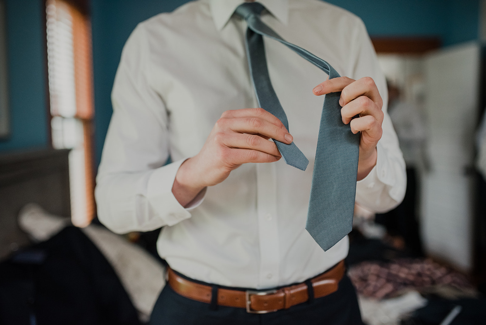 A groom ties his gray neck tie before his outdoor spring wedding ceremony at Blue Hill Farm in Waterford, VA. 