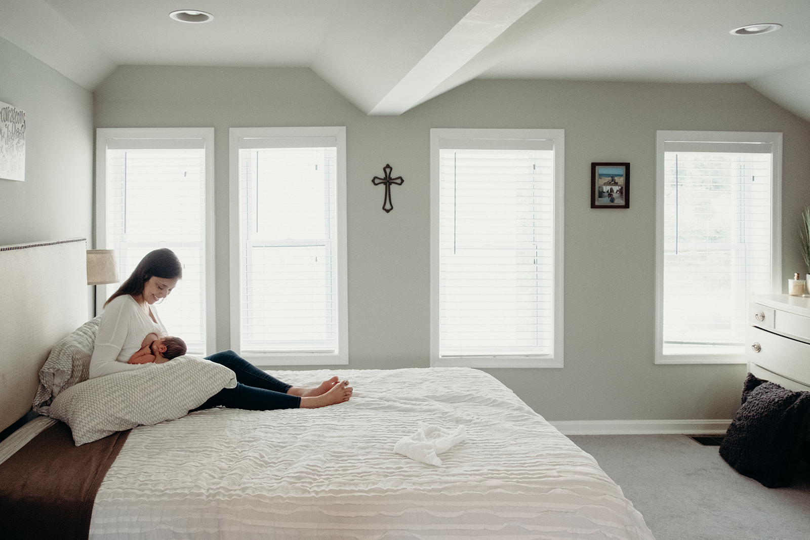 A mother nurses her newborn son on her bed in her home in DC during an in-home family photography session. 