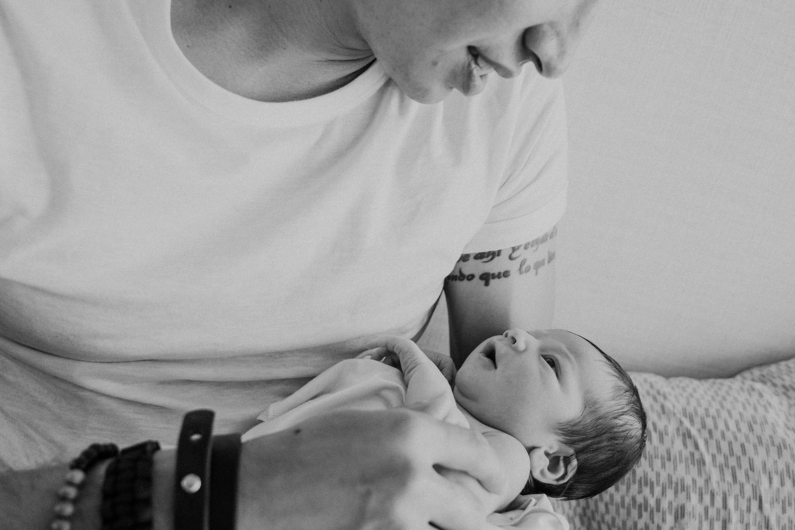 A father looks at his newborn son during an in home family photography session. 