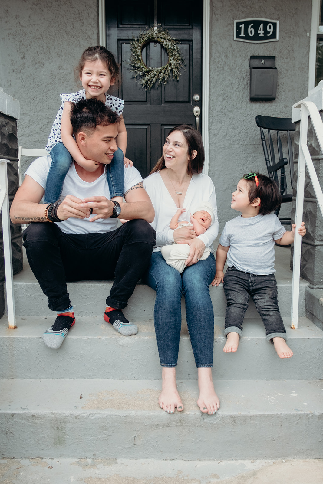 A family enjoys their front porch while snuggling their newborn in DC during an in home family photography session. 