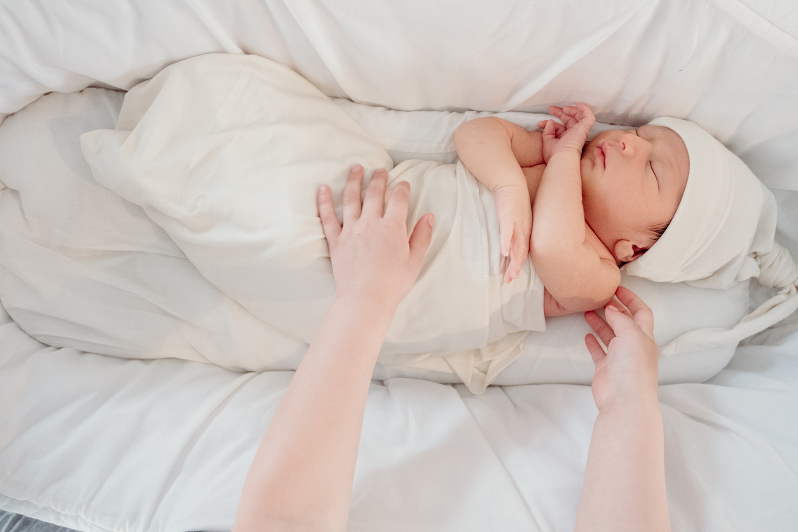 A little girl reaches out for her baby brother in his bassinet during an in-home family photography session. 