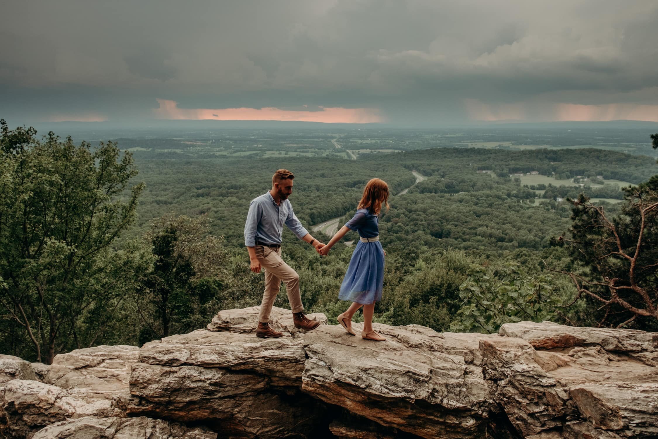 Couple walks along cliff overlooks holding hands at Bears Den Overlook