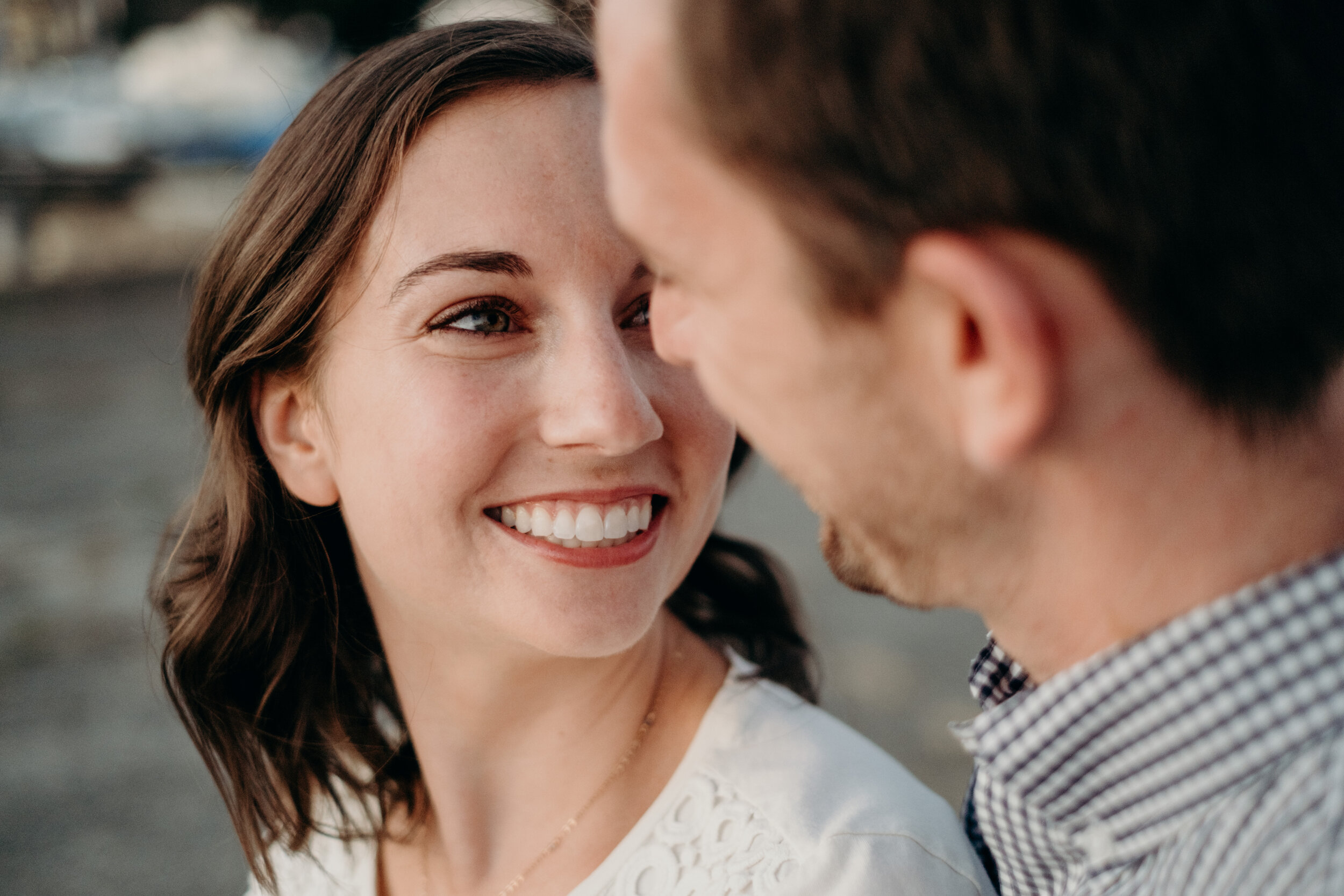 A woman smiles at her fiancé during their engagement photo session in Baltimore, MD.