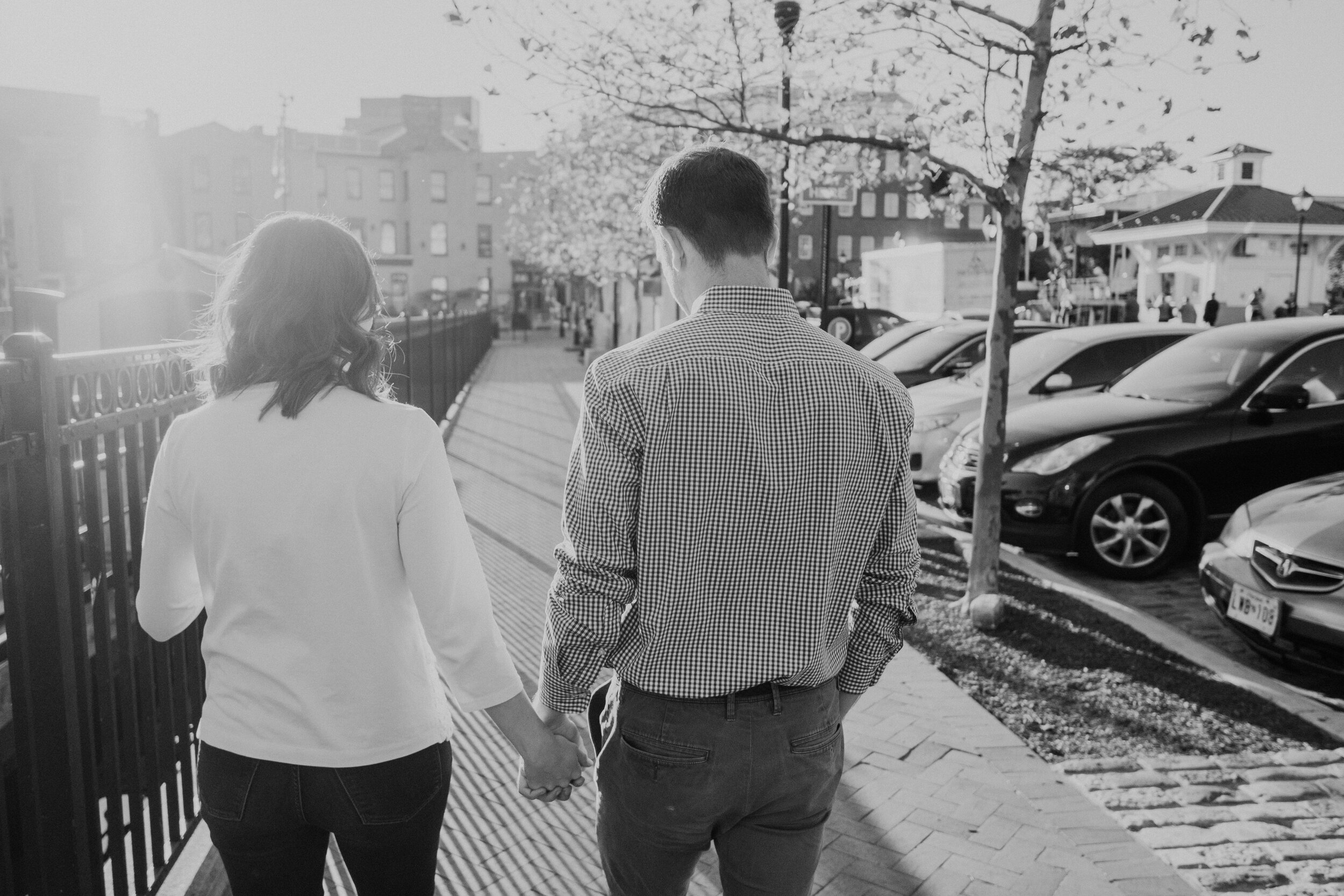 An engaged couple holds hands as they walk down the streets of the Inner Harbor in Baltimore, MD.