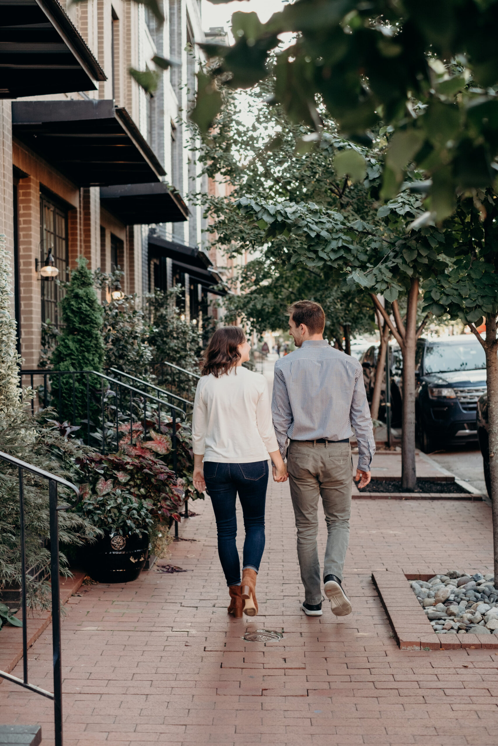 An engaged couple walks down a brick sidewalk in Baltimore, MD. 