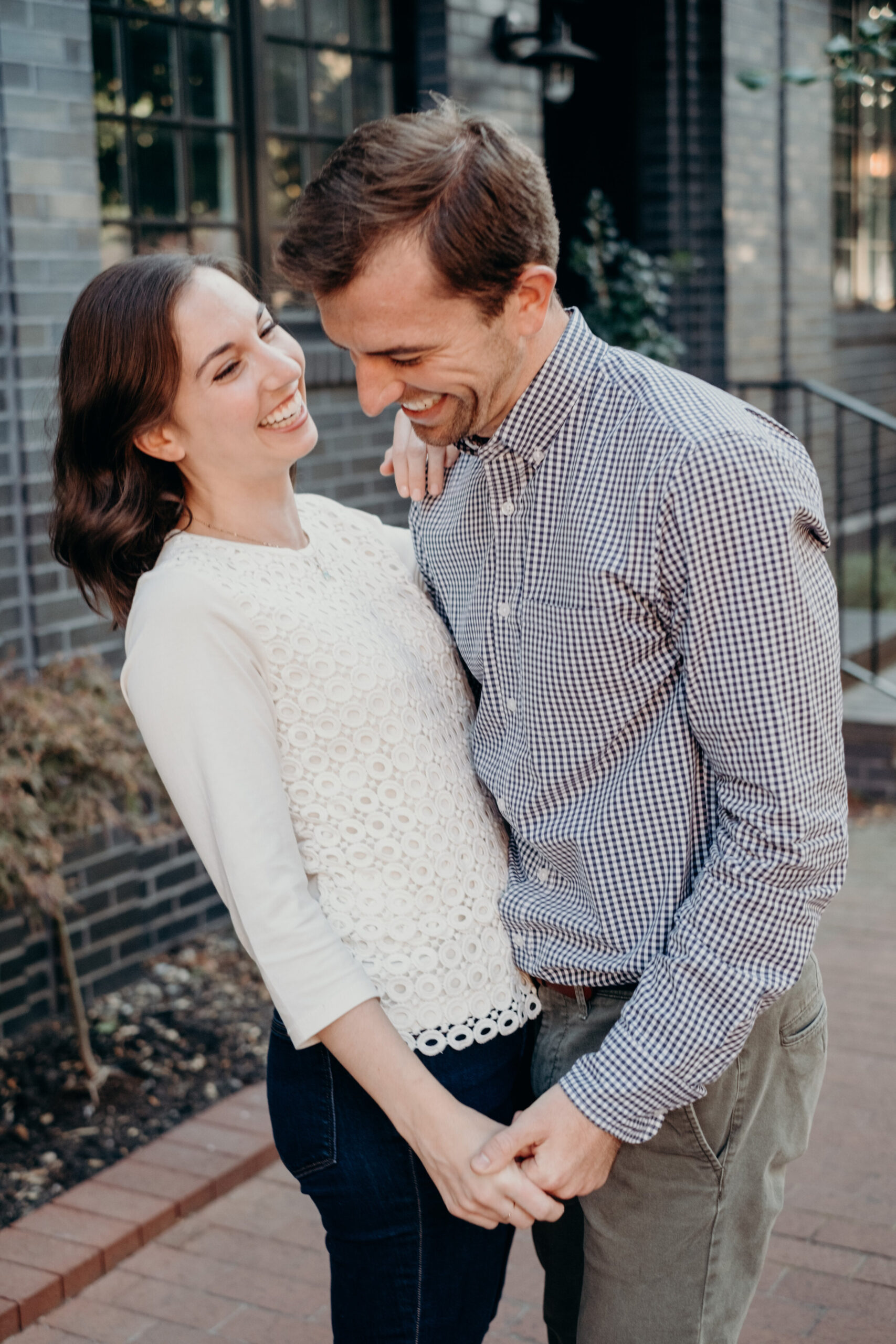 An engaged couple dances together on a brick sidewalk in Baltimore, MD. 