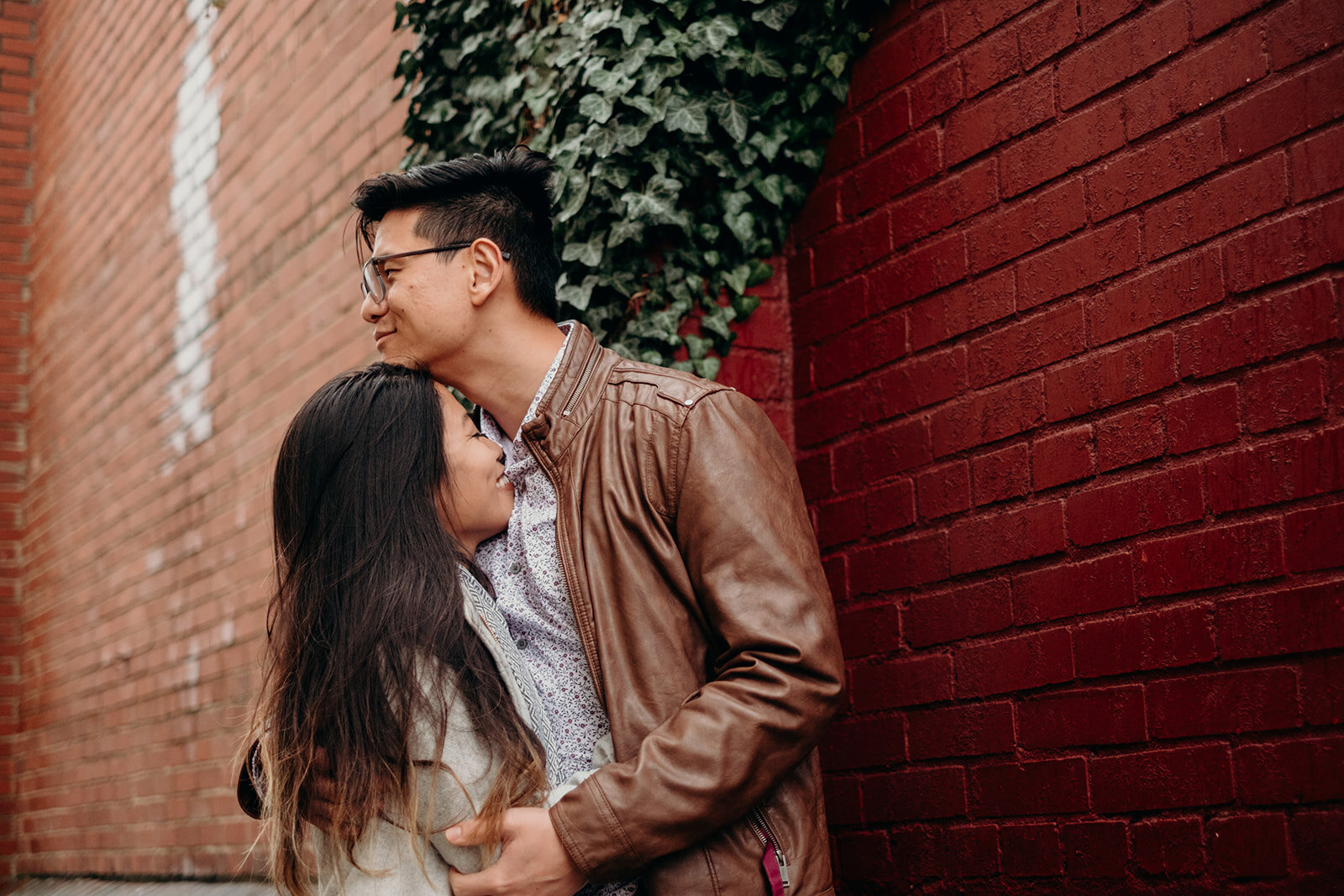 A woman cuddles with her fiancé in an ivy-lined alley during their engagement photo session in downtown Leesburg, VA. 