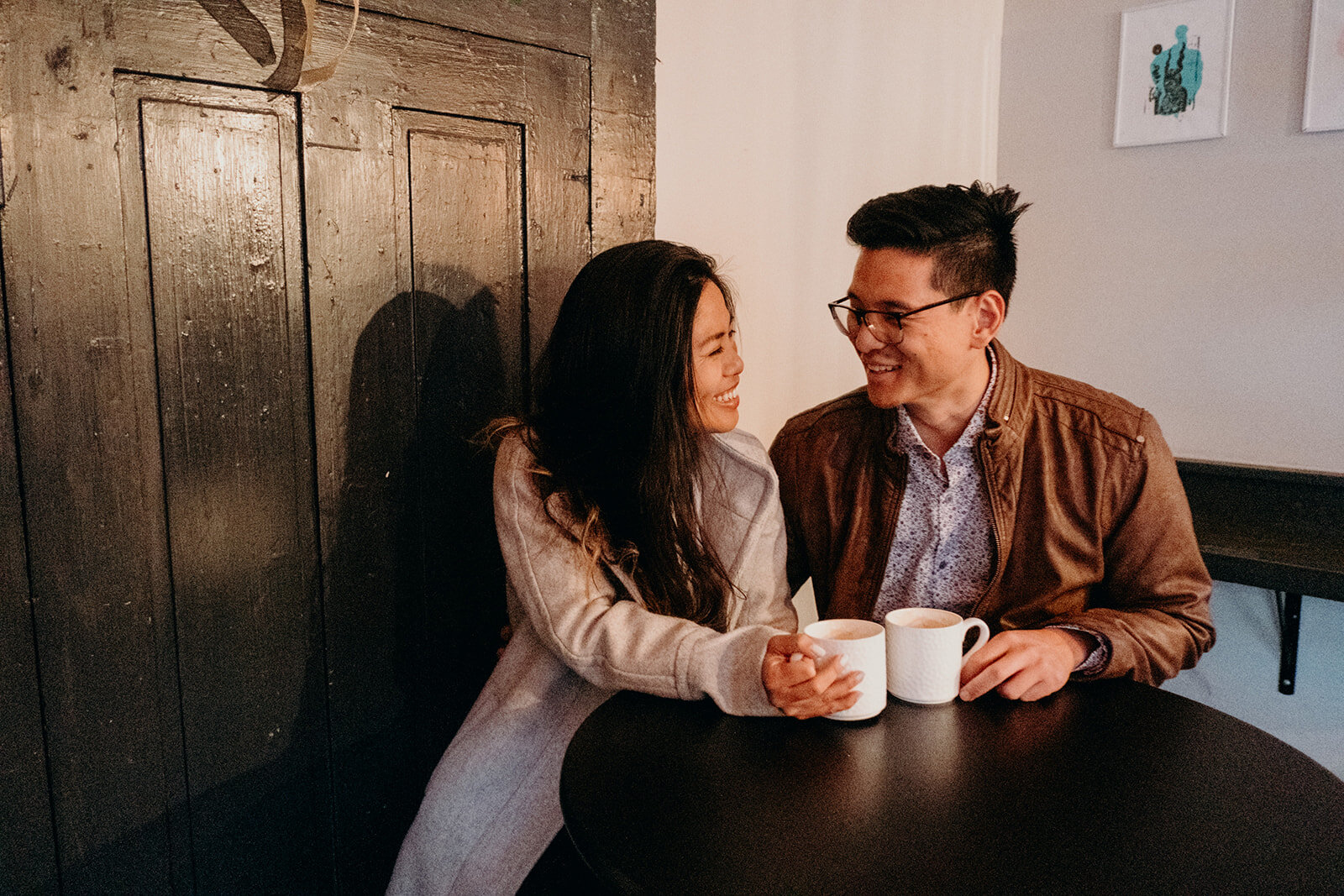 A man and his fiancé share a smile and a coffee at SideBar Coffee shop in downtown Leesburg, VA during their engagement session.