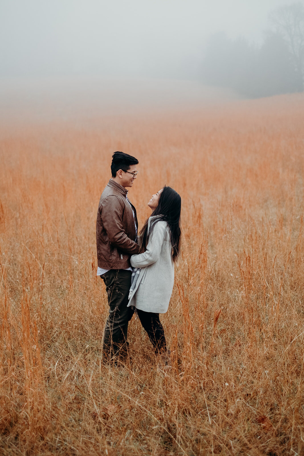 An engaged couple stands in a foggy, grassy field at Morven Park in Leesburg, VA during their engagement photo session. 