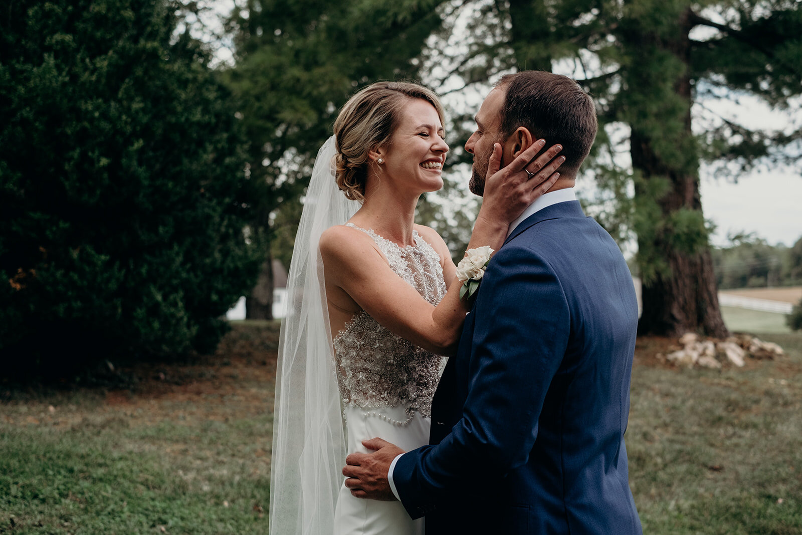 A bride holds her groom's face during their first look before their outdoor garden wedding at the Retreat at Eastwood Farm in Warrenton, VA.