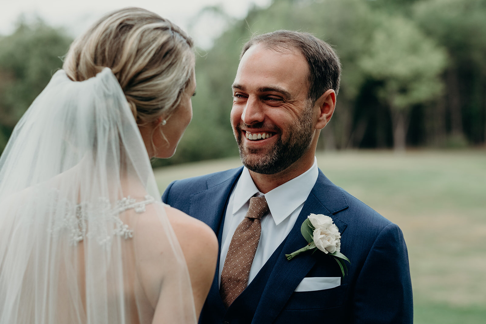 A groom smiles at his bride during their first look before their outdoor garden wedding at the Retreat at Eastwood Farm in Warrenton, VA.