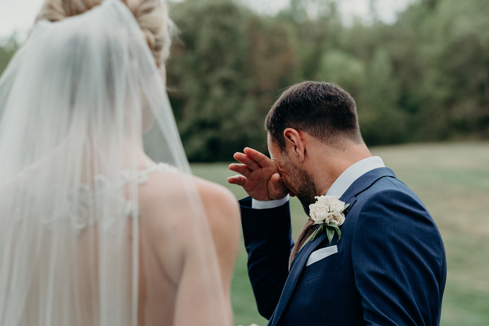 A groom wipes away a tear during his first look with his bride before their outdoor garden wedding at the Retreat at Eastwood Farm in Warrenton, VA.