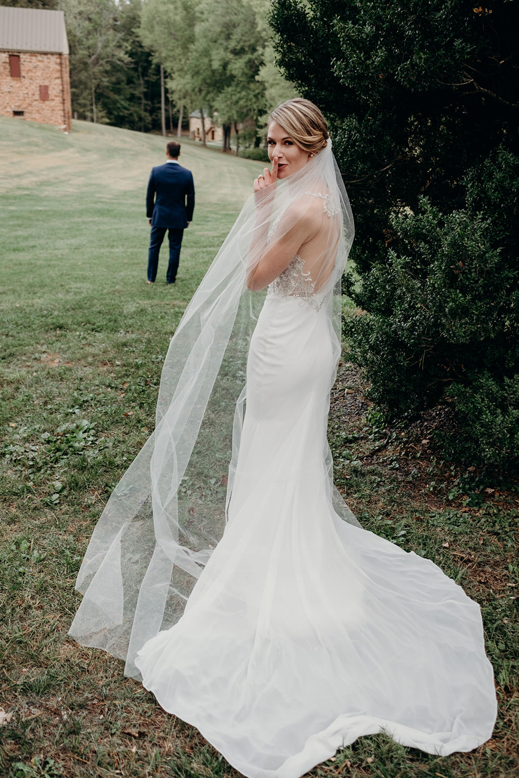 A bride in a beaded satin dress and cathedral length veil gets ready to see her groom before their outdoor garden wedding at the Retreat at Eastwood in Warrenton, VA. 