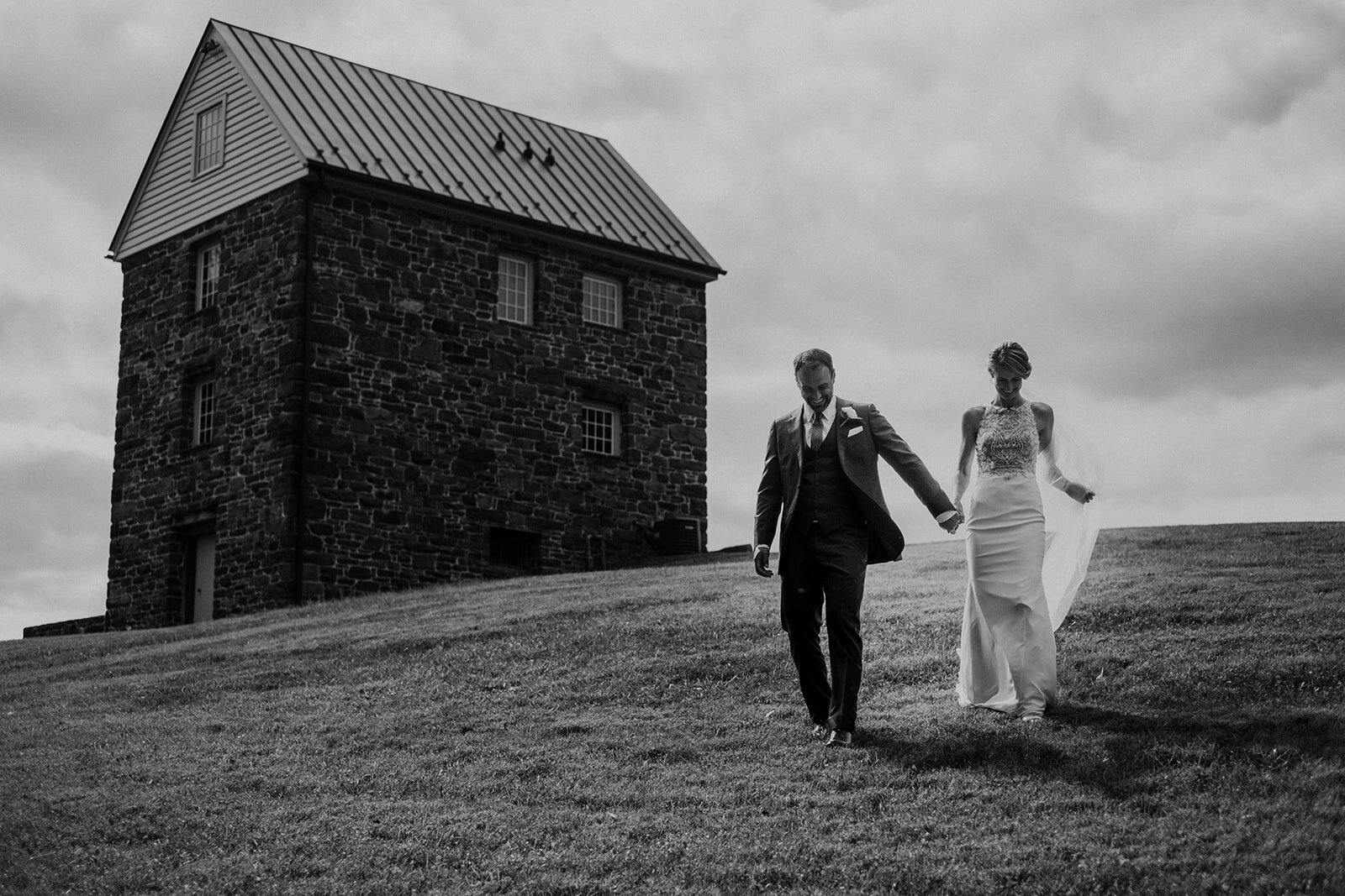 A bride and groom walk past a historic building at the Retreat at Eastwood Farm in Warrenton, VA.