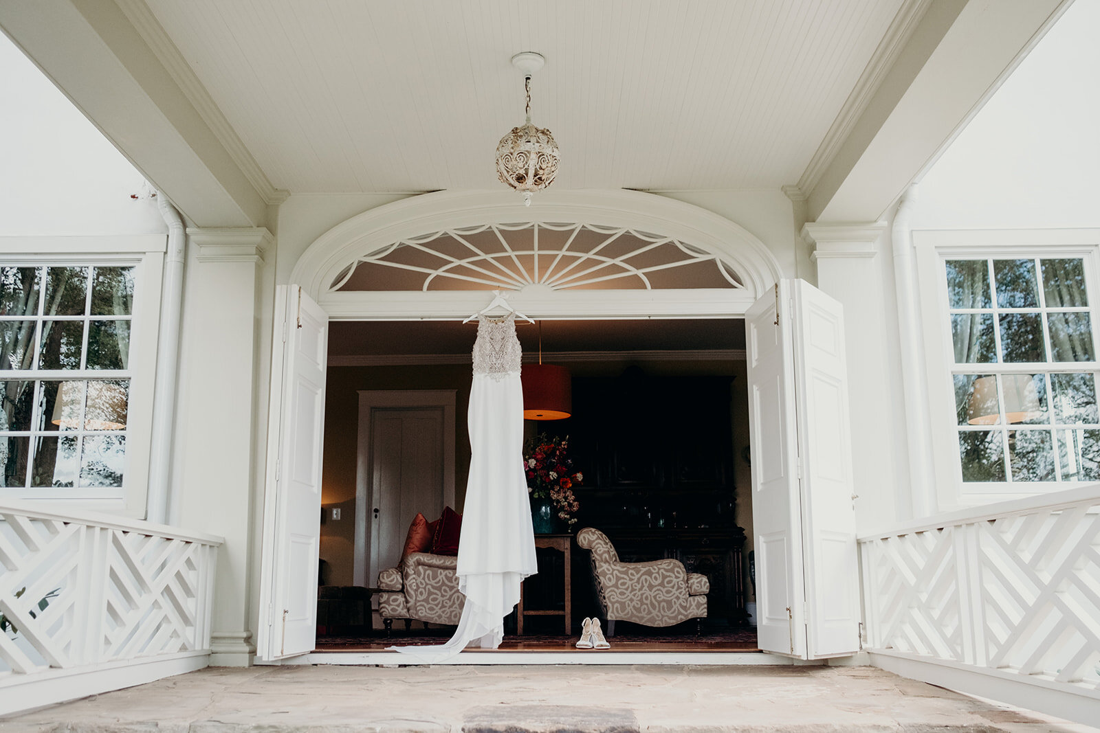 A beaded and satin wedding dress hangs in the doorway at The Retreat at Eastwood Farm in Warrenton, VA. 