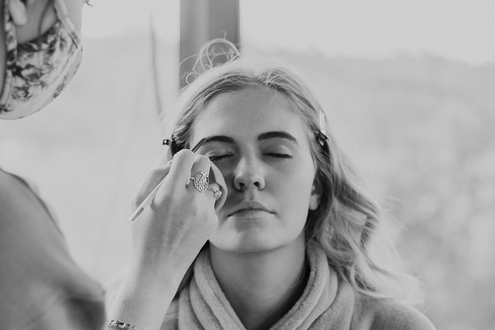 The sister of the bride gets her makeup done before the outdoor farm wedding ceremony.