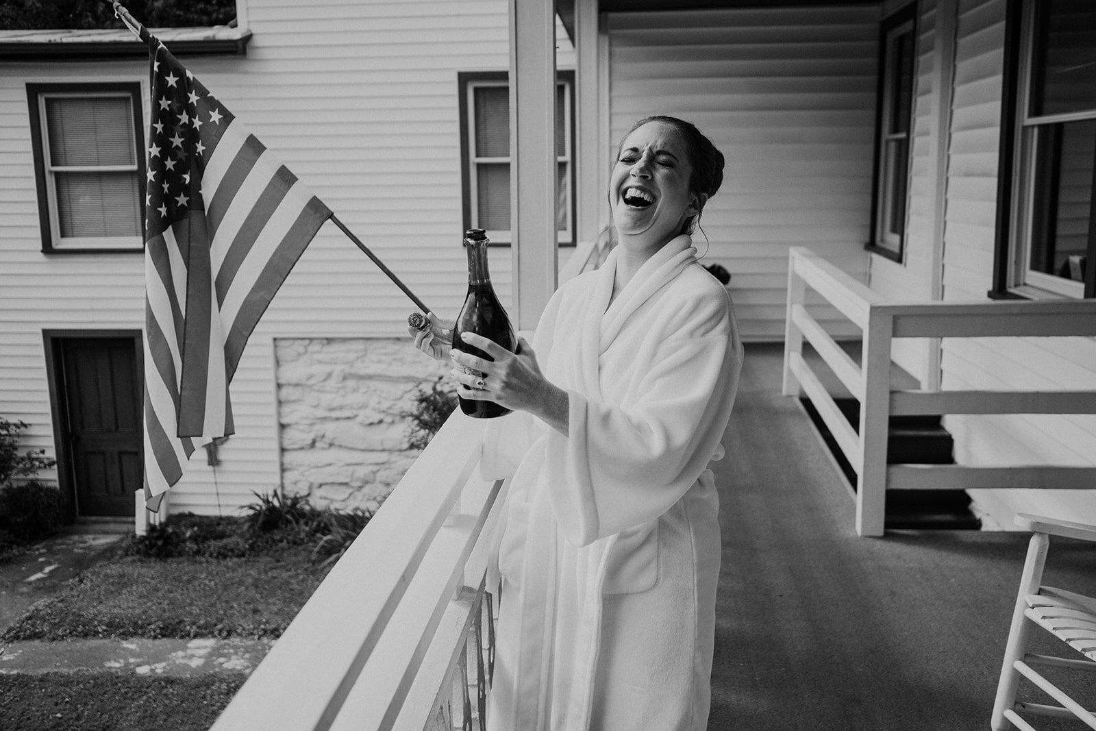 A bride pops champagne on her wedding day after getting ready for her outdoor farm wedding ceremony.