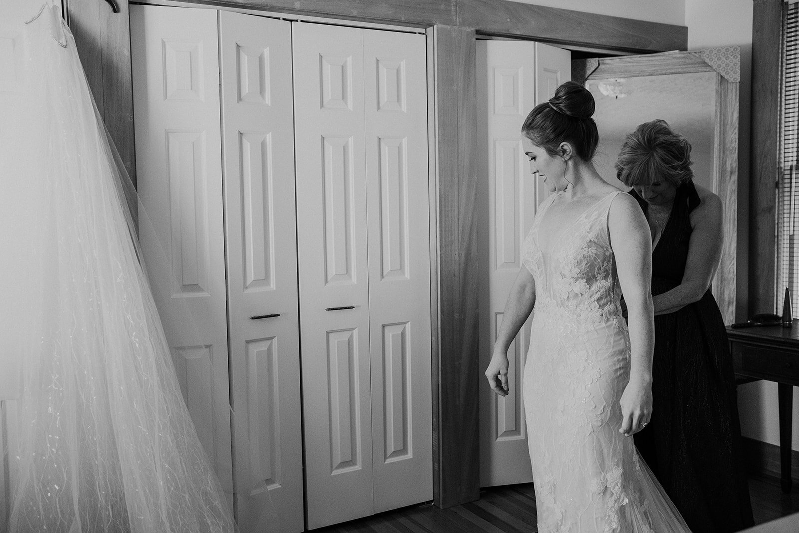 The sister of the bride helps zip up the wedding dress. 