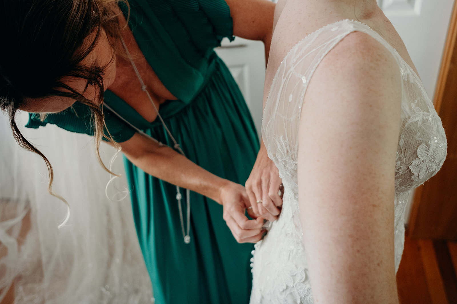 The sister of the bride zips up the dress on her wedding day. 