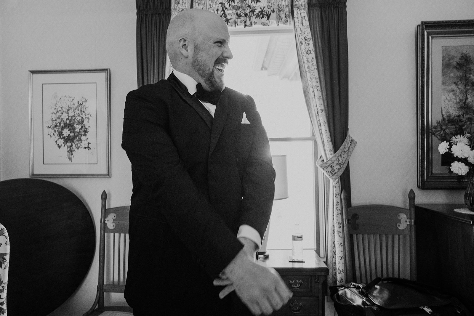 A groom smiles while getting ready for his outdoor wedding on a farm.