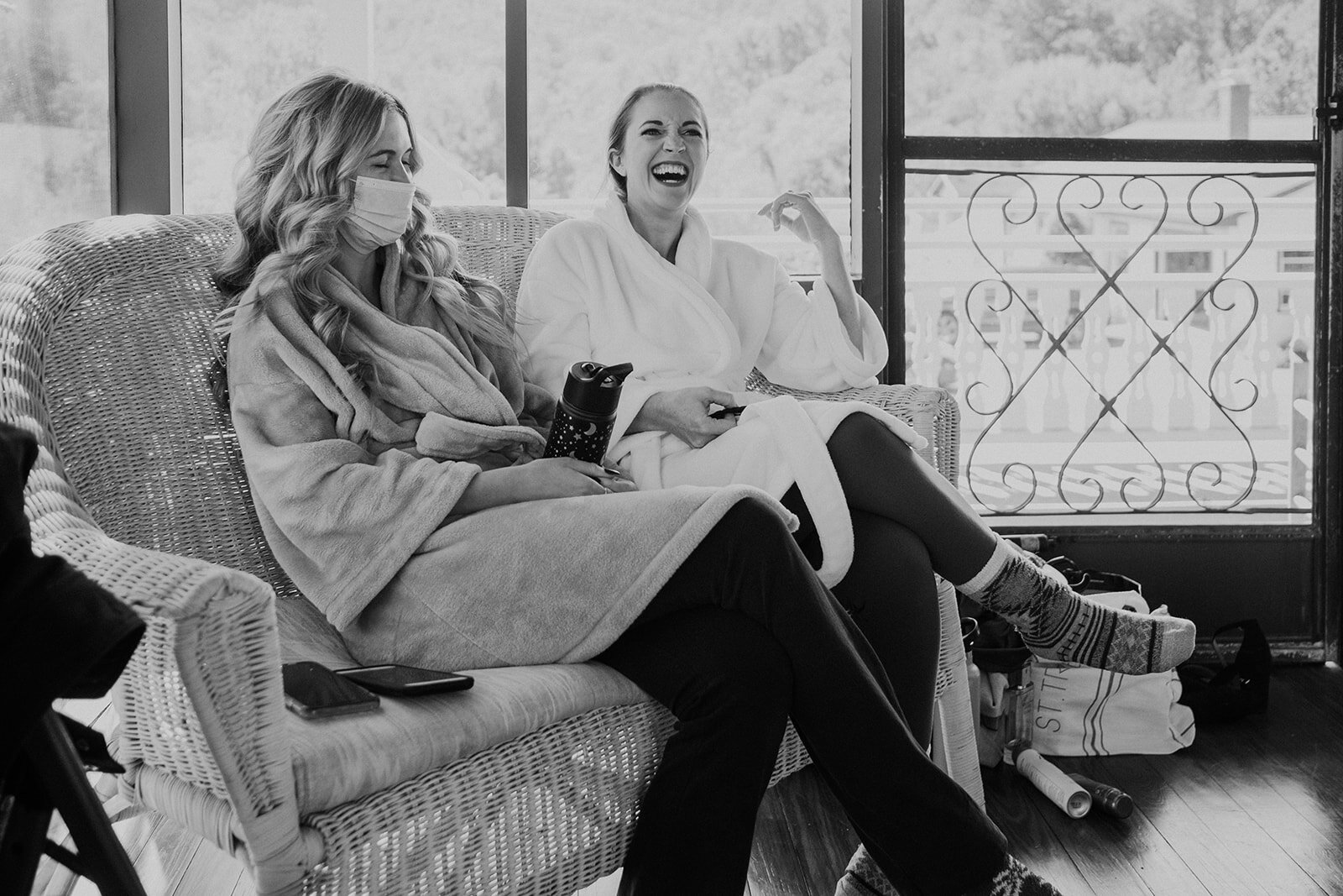 A bride laughs with her sister while they both are getting ready for an outdoor farm wedding. 