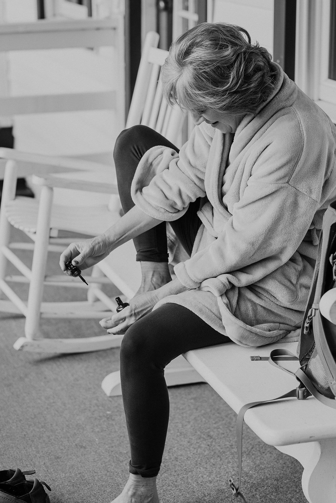 The mother of the bride touches up her toenails before the outdoor farm wedding ceremony. 