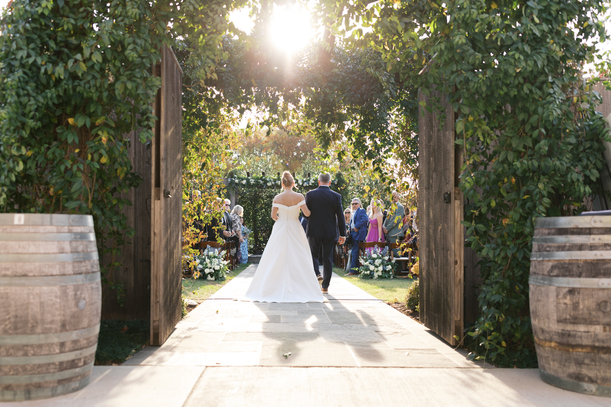 Bride walking down the aisle at fleetwood farms winery through the garden gates